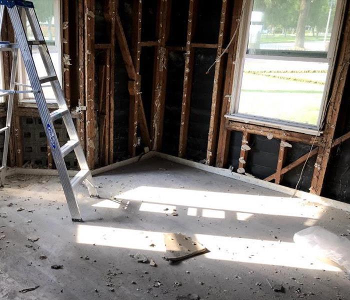 lone ladder sits in a bare room that has been reduced down to the studs