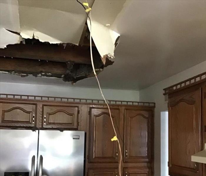 A kitchen with a collapsed ceiling. The collapse was caused by pooling rainwater