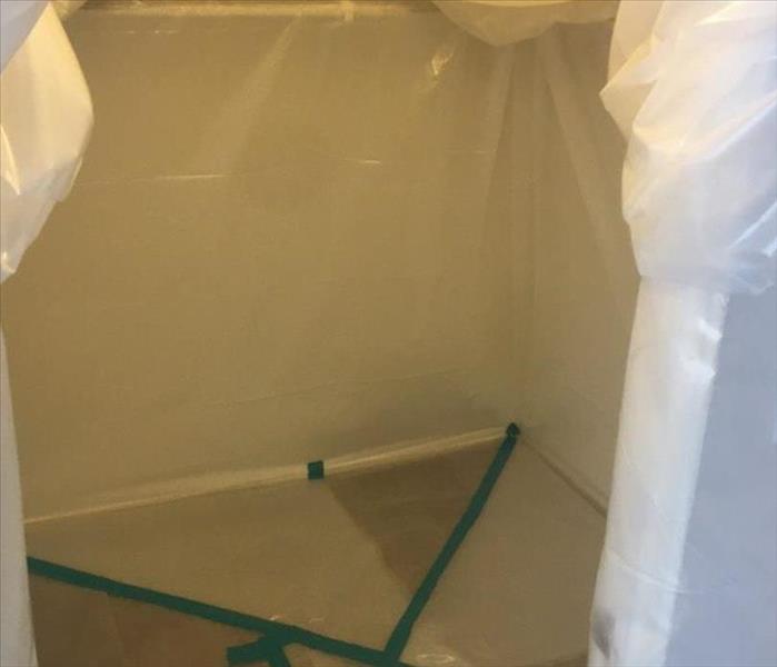 A medium-sized storage closet covered by plastic sheeting / containment.